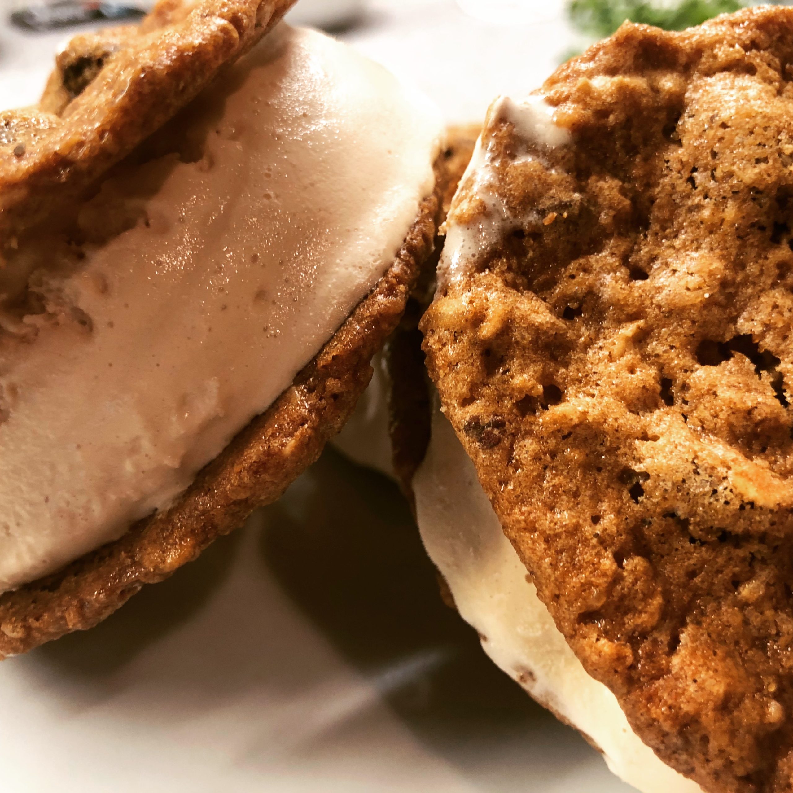 Two vanilla ice cream sandwiches made with two oatmeal chocolate chip cranberry cookies.